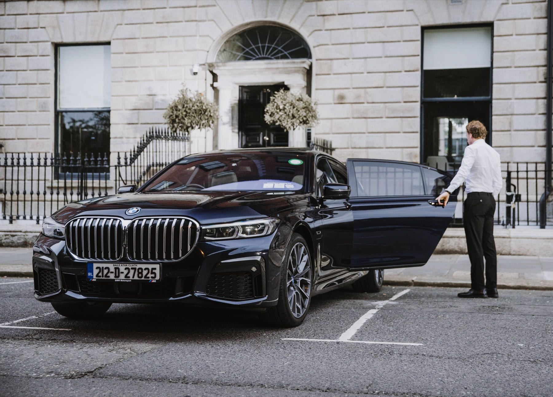 Chauffeur holding the rear door open outside a Georgian Dublin townhouse